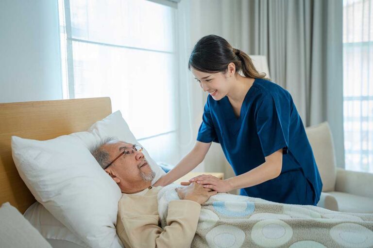 A nurse and an older adult reviewing medical charts together in a comfortable residential setting.