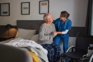 Resident writing notes while discussing a care concern with an assisted living staff member at a table.